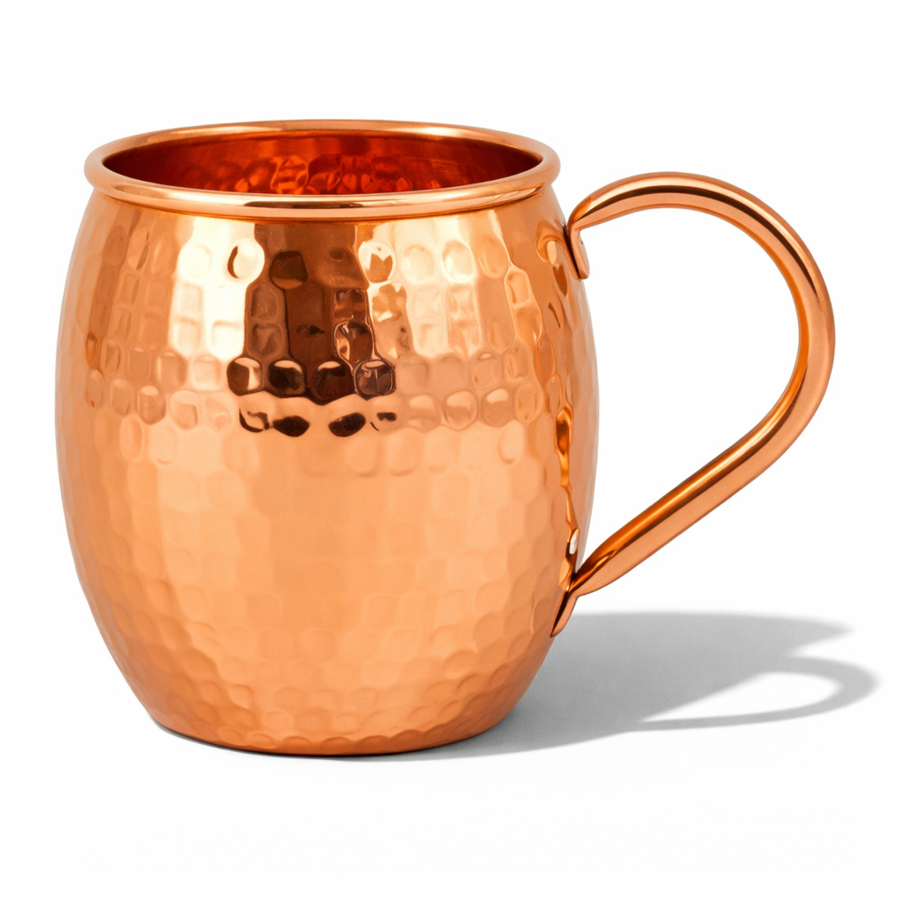 A beautiful hand-hammered shiny copper mug displayed on a table.